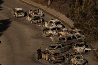 Police officers inspect cars that lie abandoned on Sunset Boulevard on Wednesday following the Palisades Fire in Palisades, California. The fire is nearly 20 percent contained
